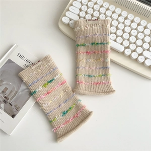 Close-up of beige ribbed knit warmers featuring colorful fringe and soft texture