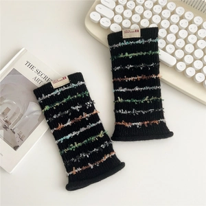 Detail of black knit sleeve with colorful fringe stripes and brand tag on white desk