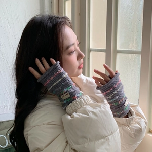 Close-up of gray knit fingerless gloves with colorful speckles and woven brand label