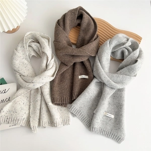 Three long speckled wool knit scarves in beige, brown, and grey with rib knit edges