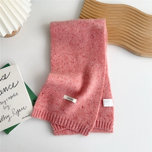 Close-up of pink 100% wool knitted scarf showing texture and care label detail