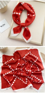 Detailed view of red silk scarf with white geometric diamond patterns and stitched edges