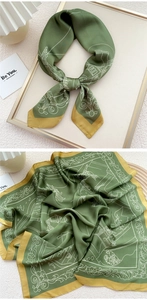 Detail of silk-like green square scarf with elegant botanical prints and golden borders