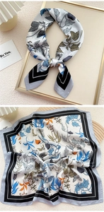 Detailed view of square silk scarf with blue floral prints and black borders