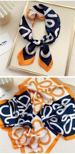 Detail view of abstract geometric silk scarf in navy and orange on a golden tray