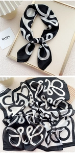Detail of silk scarf showing black and white abstract print and smooth satin texture