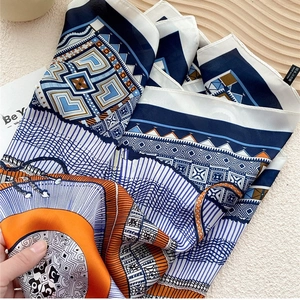 Fashionable blue and orange geometric print silk scarf displayed on a wooden surface