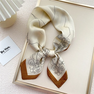 Artistic square silk scarf with figure print and brown borders on display tray
