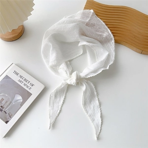 Dettaglio di sciarpa in cotone bianco a pois con eleganti bordi in pizzo smerlato