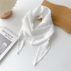 Dettaglio di sciarpa in cotone bianco con trama a pois e bordi ricamati a onde