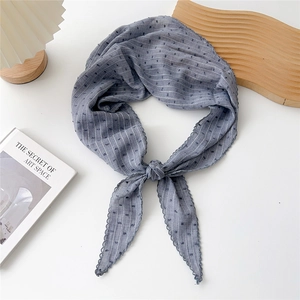 Dettaglio macro di un foulard di seta blu a pois con trama a righe e bordi merlati