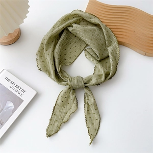 Dettaglio di un foulard in cotone verde chiaro con trama a strisce e bordi smerlati