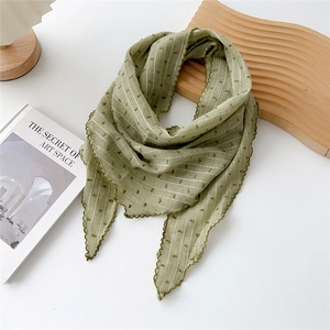 Dettaglio di un foulard in cotone e lino verde a righe bianche e bordi in pizzo
