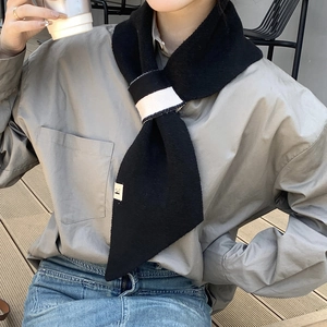 Close-up of black knitted scarf with white stripes and small decorative woven label