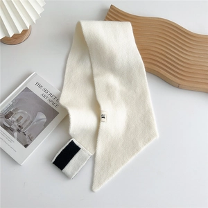 Detail of cream knit scarf with black stripes and puppy logo tag on white table