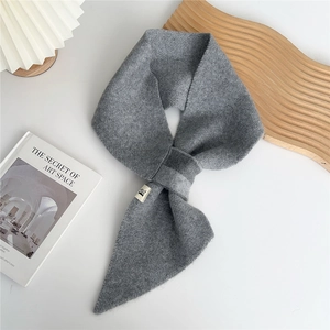 Detail of grey knitted cross scarf texture with small white woven label on white surface