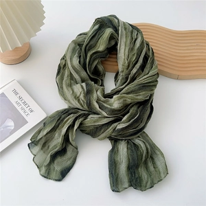 Detail of green striped crinkle scarf showing soft linen-feel fabric and pleated texture