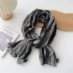 Detail of grey gradient pleated scarf showing crinkled texture on a wooden tray