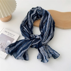 Detail of blue and grey striped scarf showing pleated texture on white background