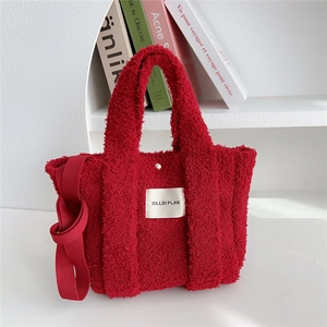 Detail shot of a red fuzzy tote bag with soft plush texture and a wide fabric strap