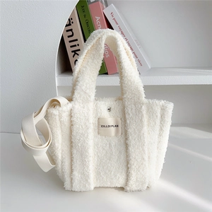 White fuzzy plush tote bag with top handles and shoulder strap in a minimalist setting
