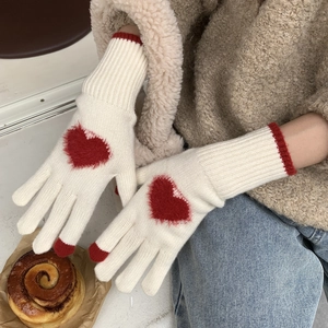 Dettaglio di guanti in maglia con cuori rossi morbidi e punta touch per inverno