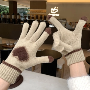 Dettaglio di guanti invernali in maglia con decoro a cuore e dita touch screen