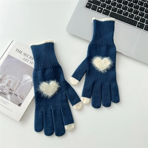 Dettaglio di guanti in maglia blu navy con cuore di peluche bianco e punte a contrasto