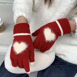 Dettaglio guanti in maglia rossi con cuore in peluche bianco e punte delle dita touch