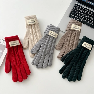 Flat lay of five-color knit gloves in cable pattern on a desk with lifestyle props