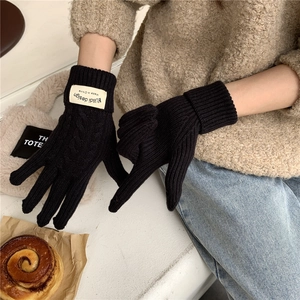 Close-up of black cable knit gloves with brand label in a cozy winter lifestyle setting