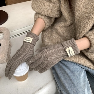 Close-up of brown cable knit glove with thick ribbed cuff and brand woven label