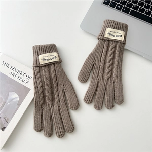 Detail of brown cable-knit winter gloves featuring a stylish fabric brand label on the cuff
