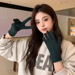Detail of dark green cable knit gloves with touch screen design and brand label