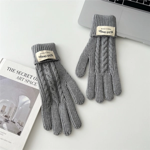 Detailed knit texture of gray winter gloves with stylish folded cuffs and brand label