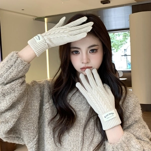 Close-up of off-white cable knit glove featuring a minimalist branded fabric label
