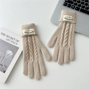 Detail of cable knit texture and branded cuff labels on warm winter touch-screen gloves