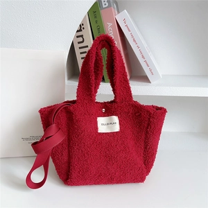 Detail of red plush tote bag showing soft teddy fabric texture and brand label