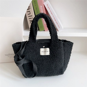 Detail of black faux shearling tote bag with brand label and long shoulder strap