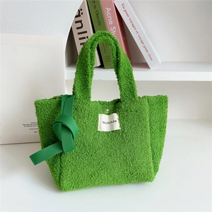 Detail of green faux shearling tote bag with brand label and knotted strap accent