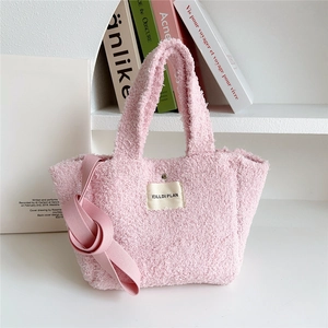 Detailed macro view of soft pink teddy fleece tote bag with brand label and metal buckle