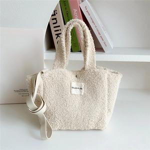 Close-up of fuzzy cream tote bag with fabric strap and rectangle brand label