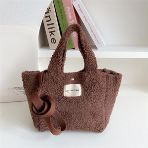 Detailed view of brown plush crossbody bag with soft faux fur texture and woven label