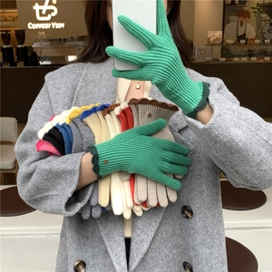 Détail de gants en maille côtelée colorée avec bords festonnés et boutons dorés