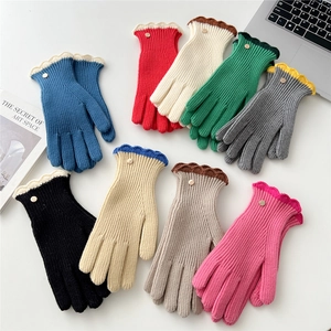 Détail de gants tricotés avec bordure ondulée contrastée et bouton doré vintage