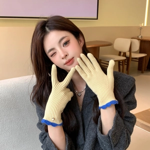 Gros plan de gants en maille beige avec poignets ondulés bleus et bouton doré