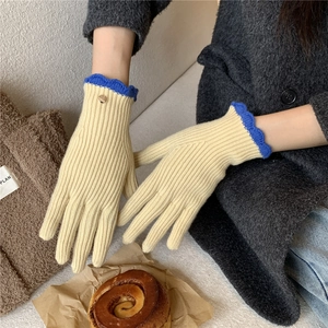 Détail d'un gant en tricot avec poignet à volant bleu marine et bouton métallique