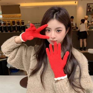 Gros plan de gants en tricot rouge avec poignets festonnés blancs et texture à rayures