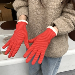 Détail d'un gant en tricot rouge avec bord festonné blanc et texture côtelée