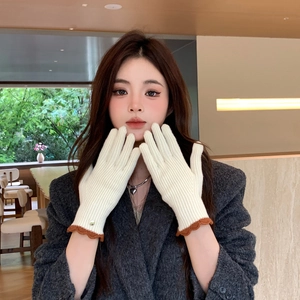 Détail de gants en maille avec bordure festonnée contrastée et petit bouton métallique